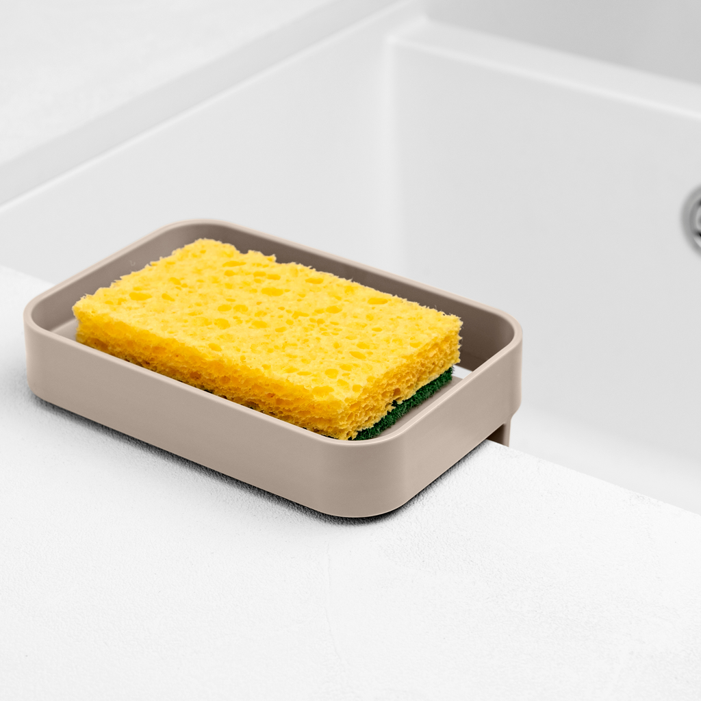 Blim+ Battigia Sponge Holder in taupe holding a yellow sponge beside a sink