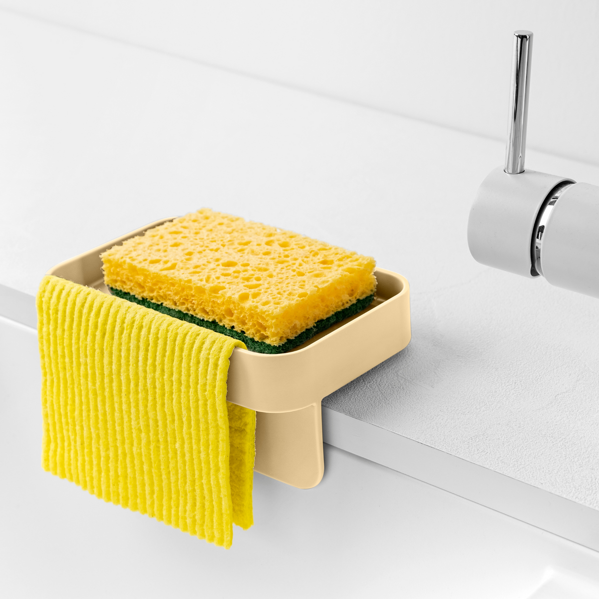 Blim+ Battigia Sponge Holder in cream holding a sponge and yellow cloth at a sink