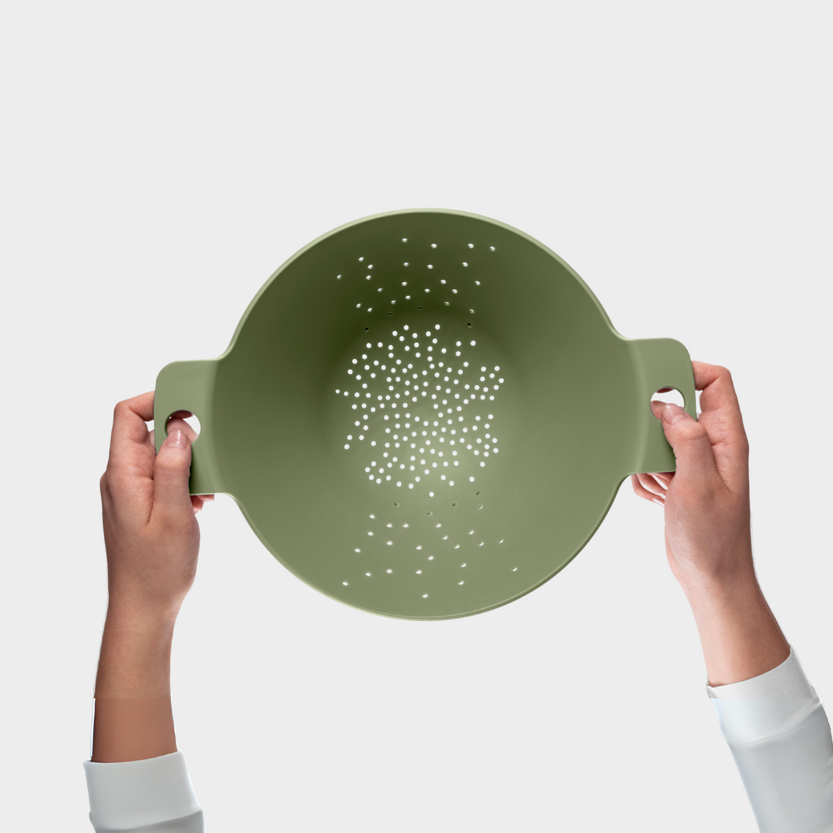 Blim+ Cosmo Colander Medium in green, held up in both hands, seen from the front