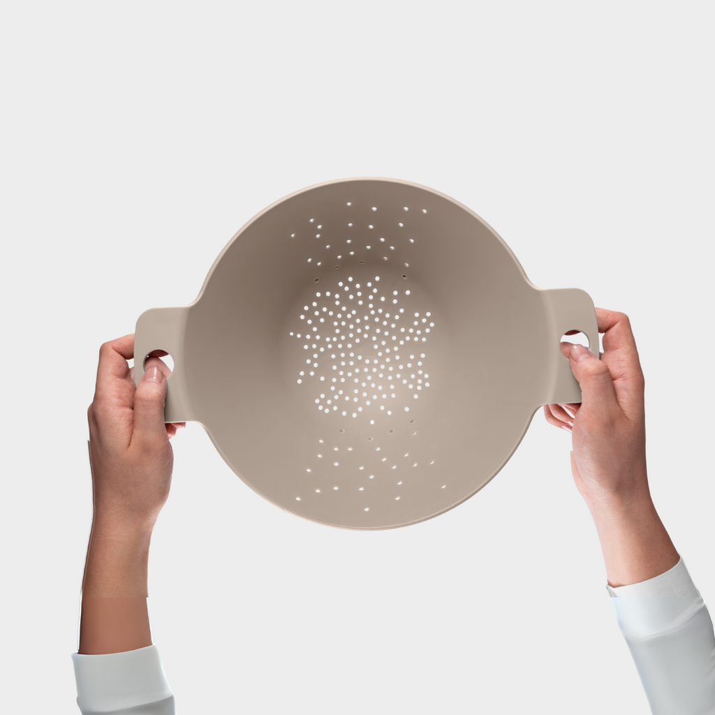 Blim+ Cosmo Colander Medium in taupe, held up in both hands, seen from the front