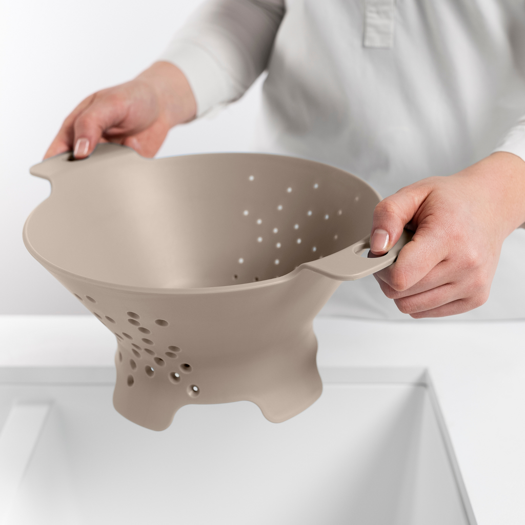 Blim+ Cosmo Colander Medium in taupe, held over a sink