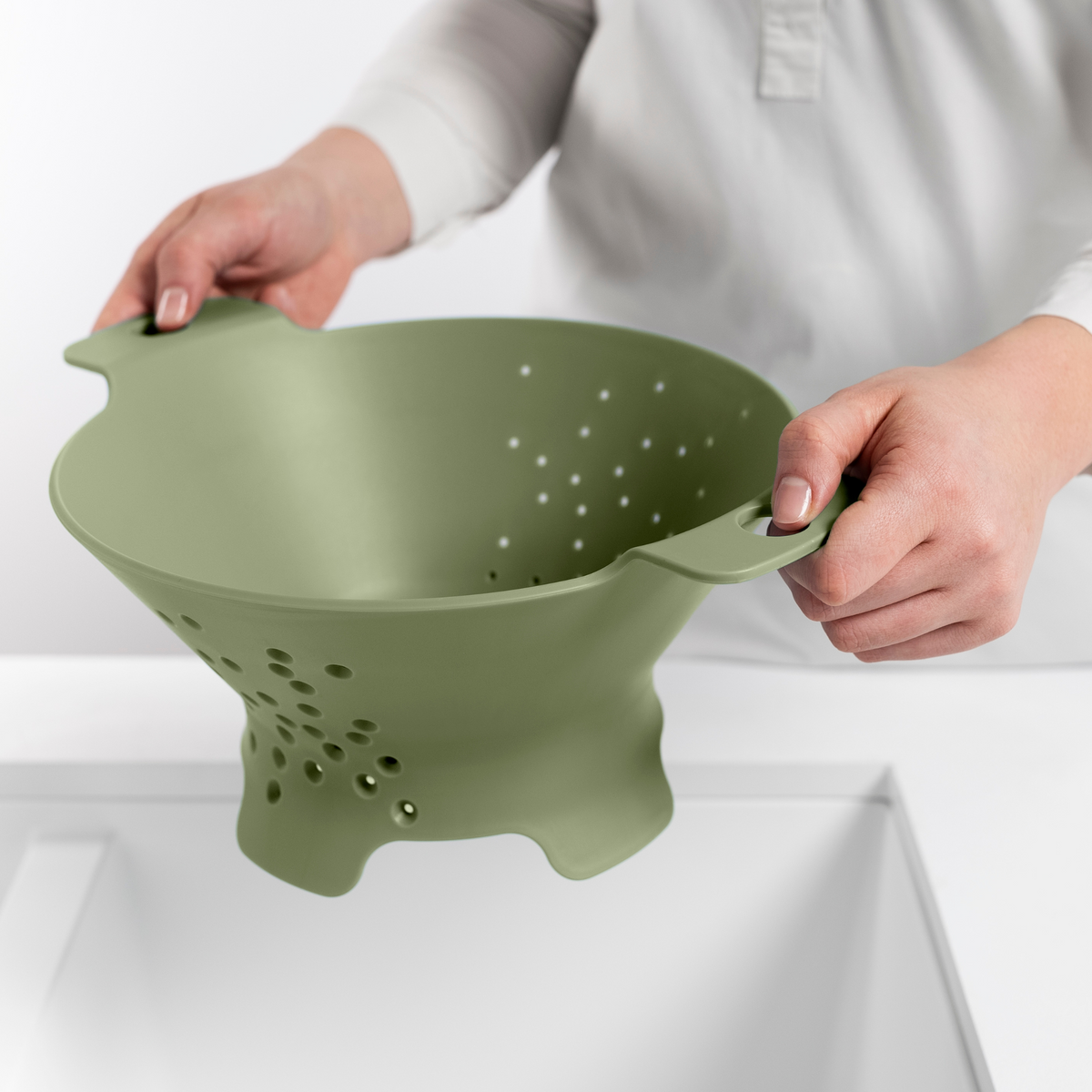 Blim+ Cosmo Colander Medium in green, held over a sink