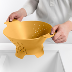 Blim+ Cosmo Colander Medium in yellow, held over a sink