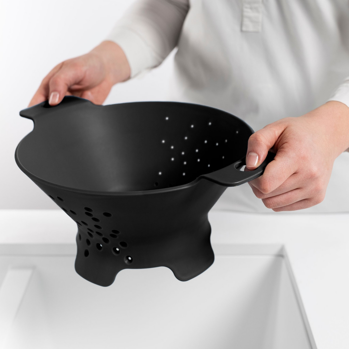 Blim+ Cosmo Colander Medium in black, held over a sink