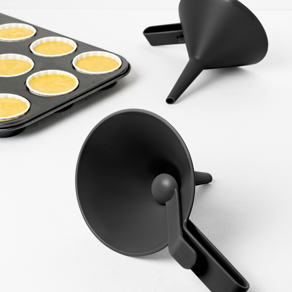 Blim+ Dolina Funnel in black, beside a muffin tray