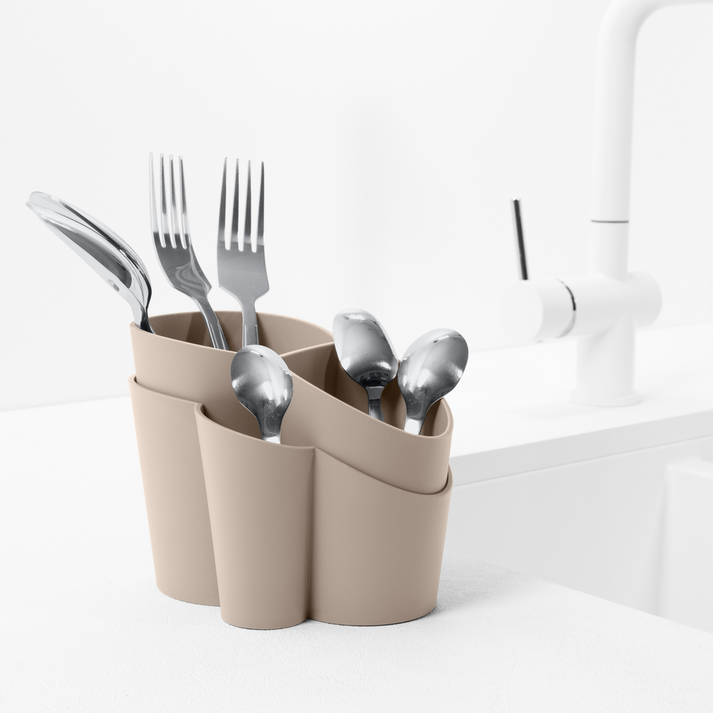 Blim+ Gocciolo Cutlery Drainer in taupe, holding cutlery beside a tap
