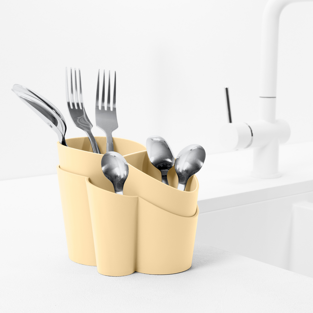 Blim+ Gocciolo Cutlery Drainer in pale yellow, holding cutlery beside a tap