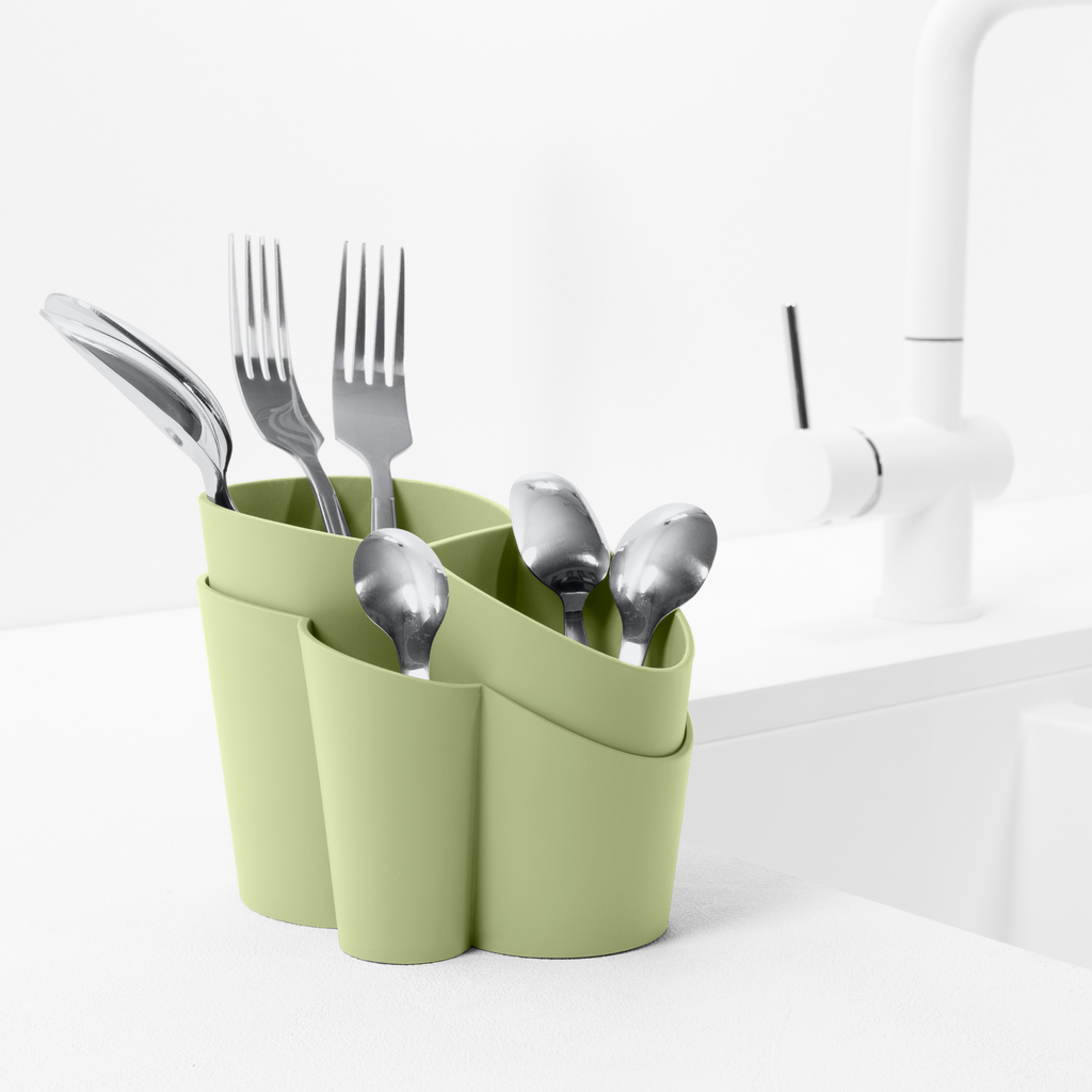 Blim+ Gocciolo Cutlery Drainer in green, holding cutlery beside a tap