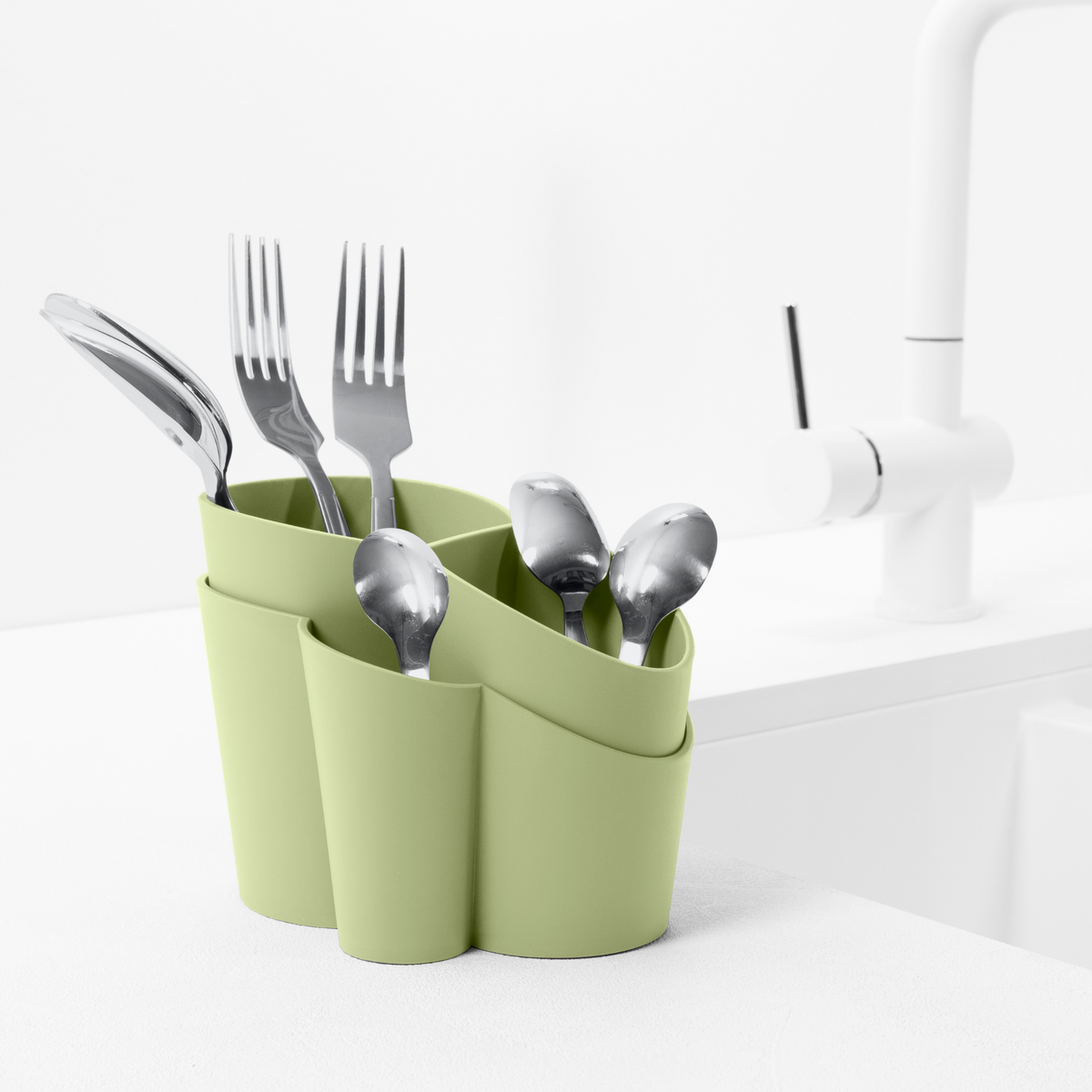Blim+ Gocciolo Cutlery Drainer in green, holding cutlery beside a tap