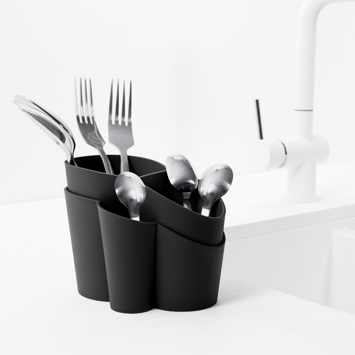 Blim+ Gocciolo Cutlery Drainer in black, holding cutlery beside a tap