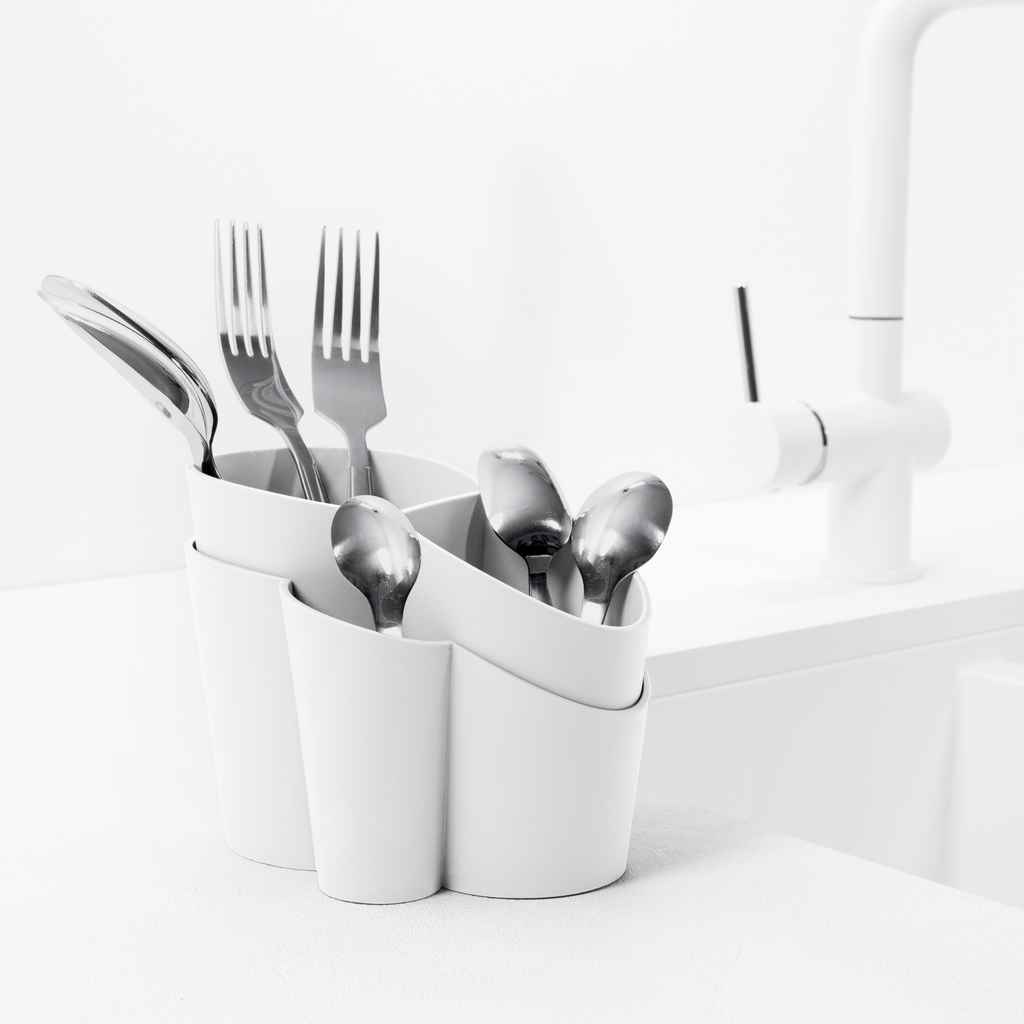 Blim+ Gocciolo Cutlery Drainer in white, holding cutlery beside a tap