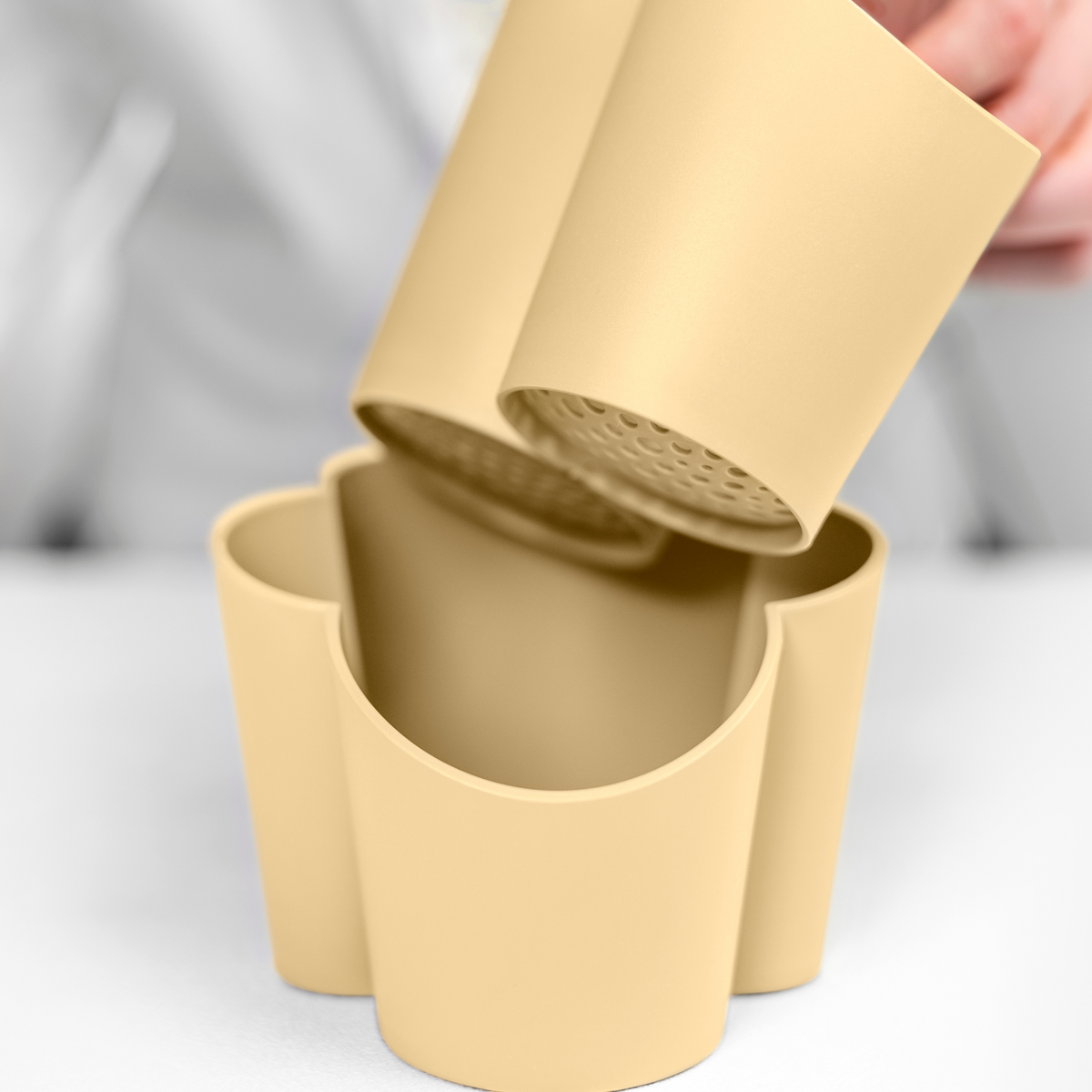 Blim+ Gocciolo Cutlery Drainer in pale yellow, with the top part being lifted by hand