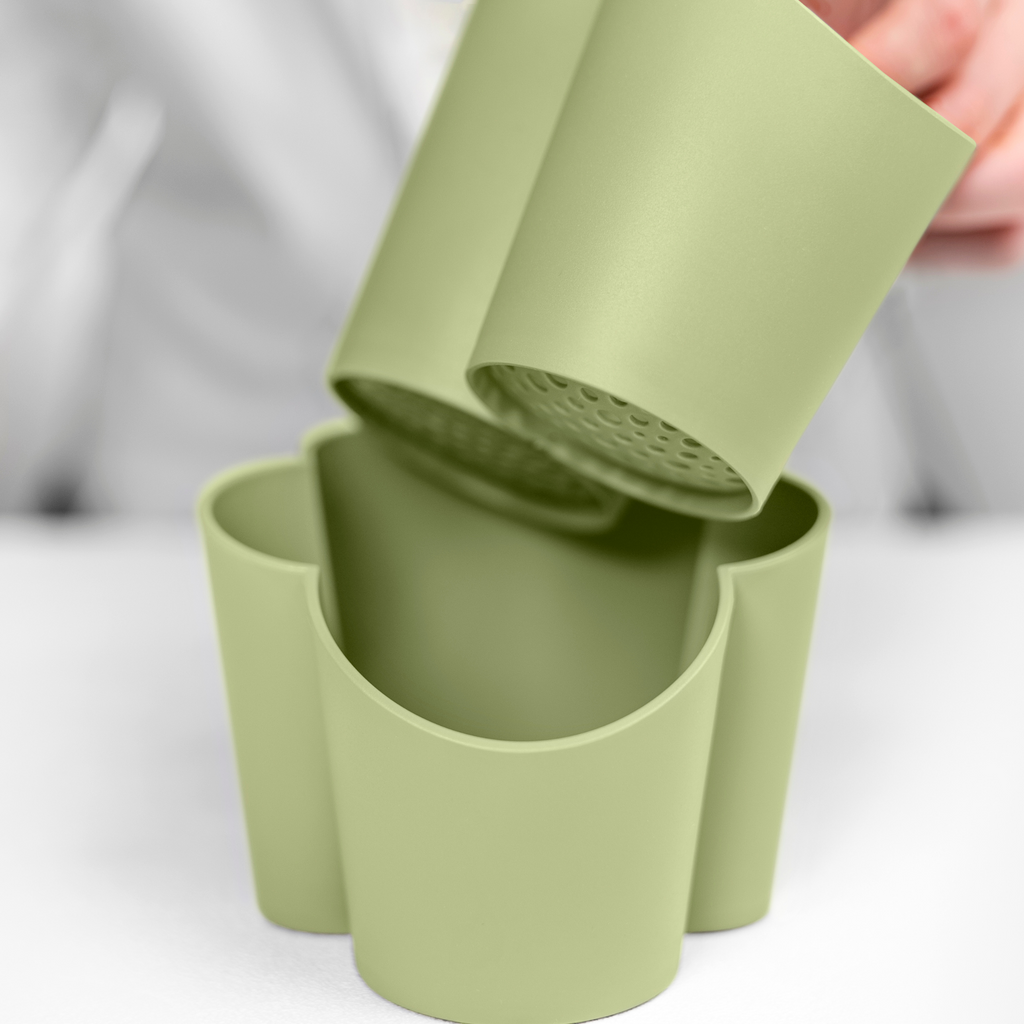 Blim+ Gocciolo Cutlery Drainer in green, with the top part being lifted by hand