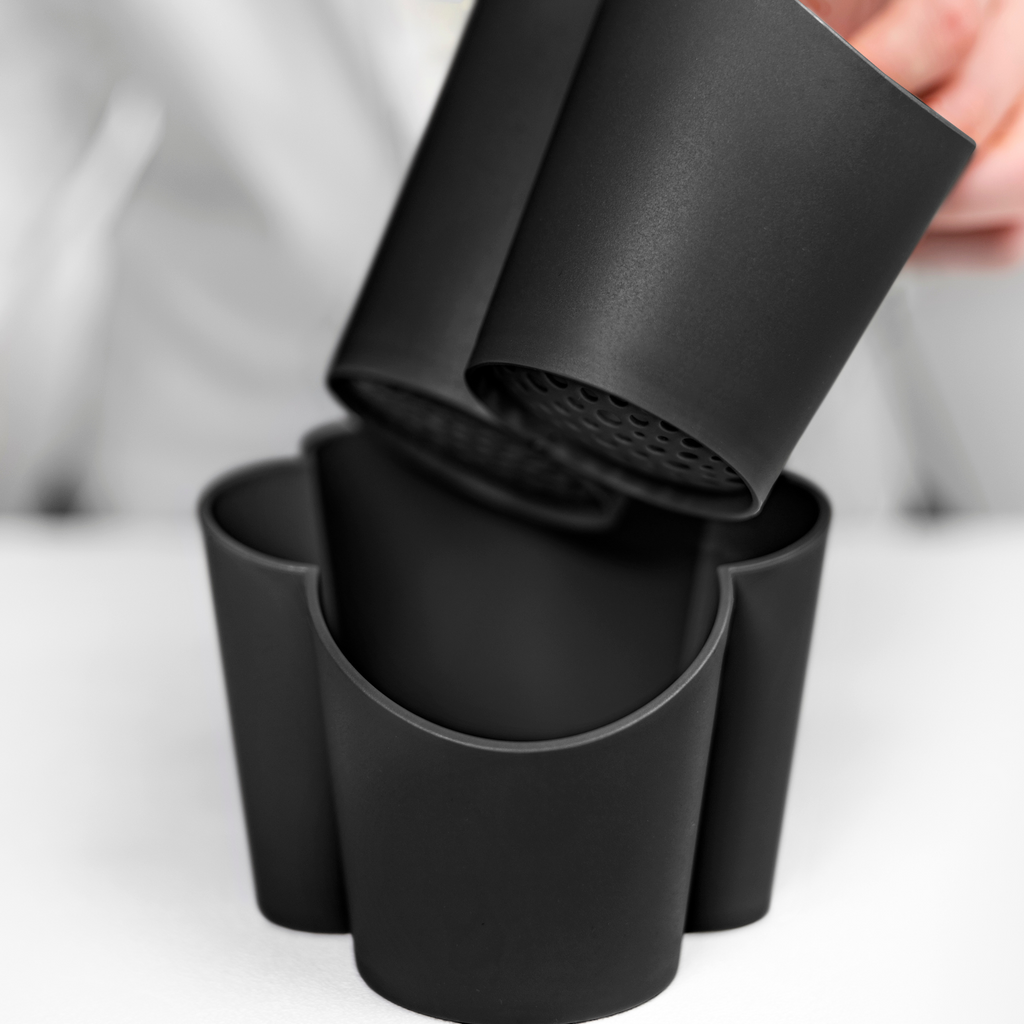Blim+ Gocciolo Cutlery Drainer in black, with the top part being lifted by hand