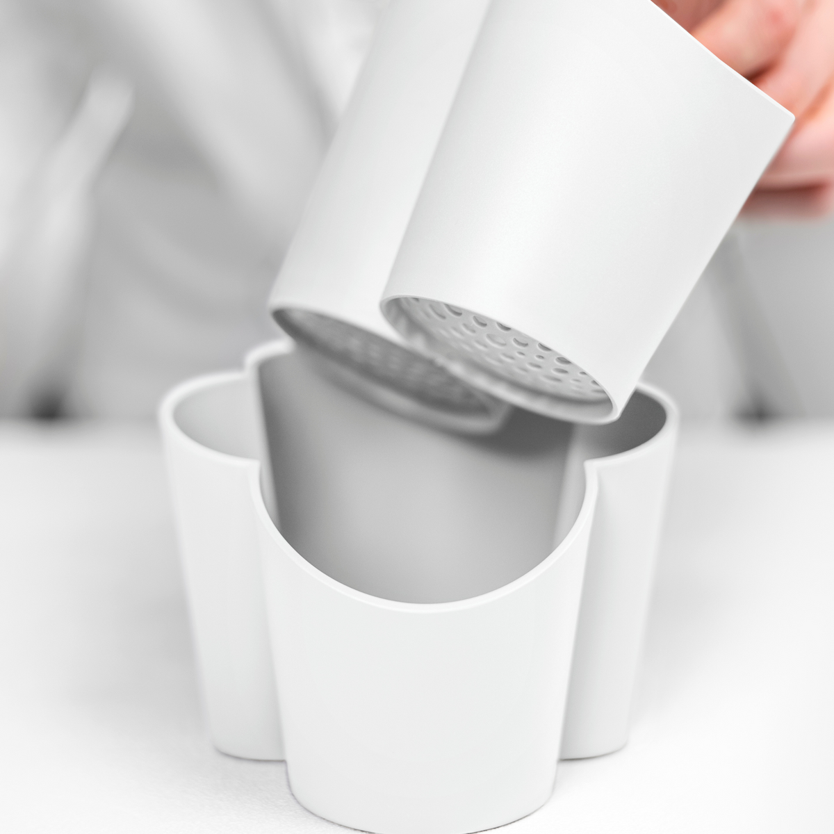 Blim+ Gocciolo Cutlery Drainer in white, with the top part being lifted by hand