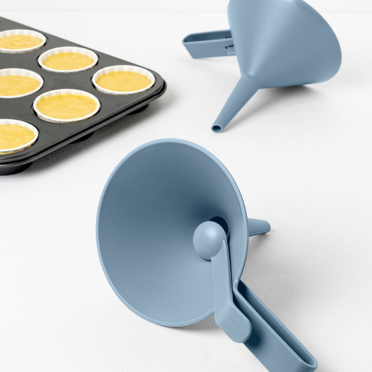 Blim+ Dolina Funnel in blue, beside a muffin tray