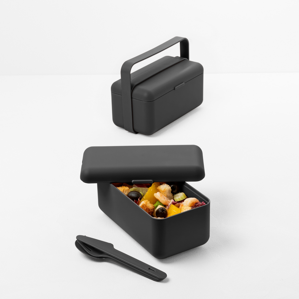 Blim+ Lunchbox Bauletto Small in black with the handle raised, holding snacks, with cutlery