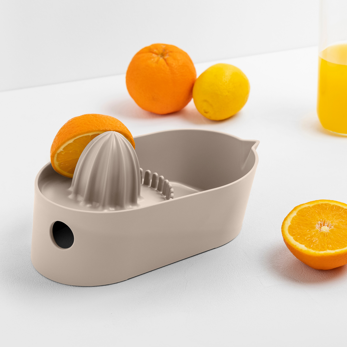 Blim+ Oblo' Juicer in taupe, beside fresh oranges