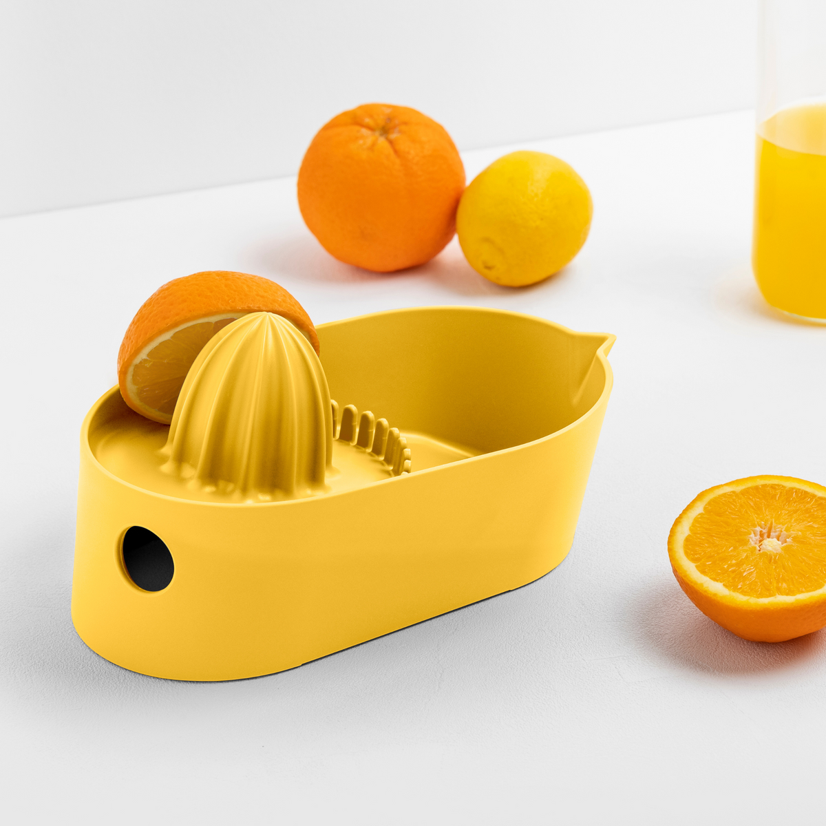 Blim+ Oblo' Juicer in yellow, beside fresh oranges