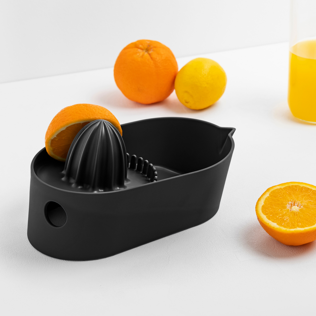 Blim+ Oblo' Juicer in black, beside fresh oranges