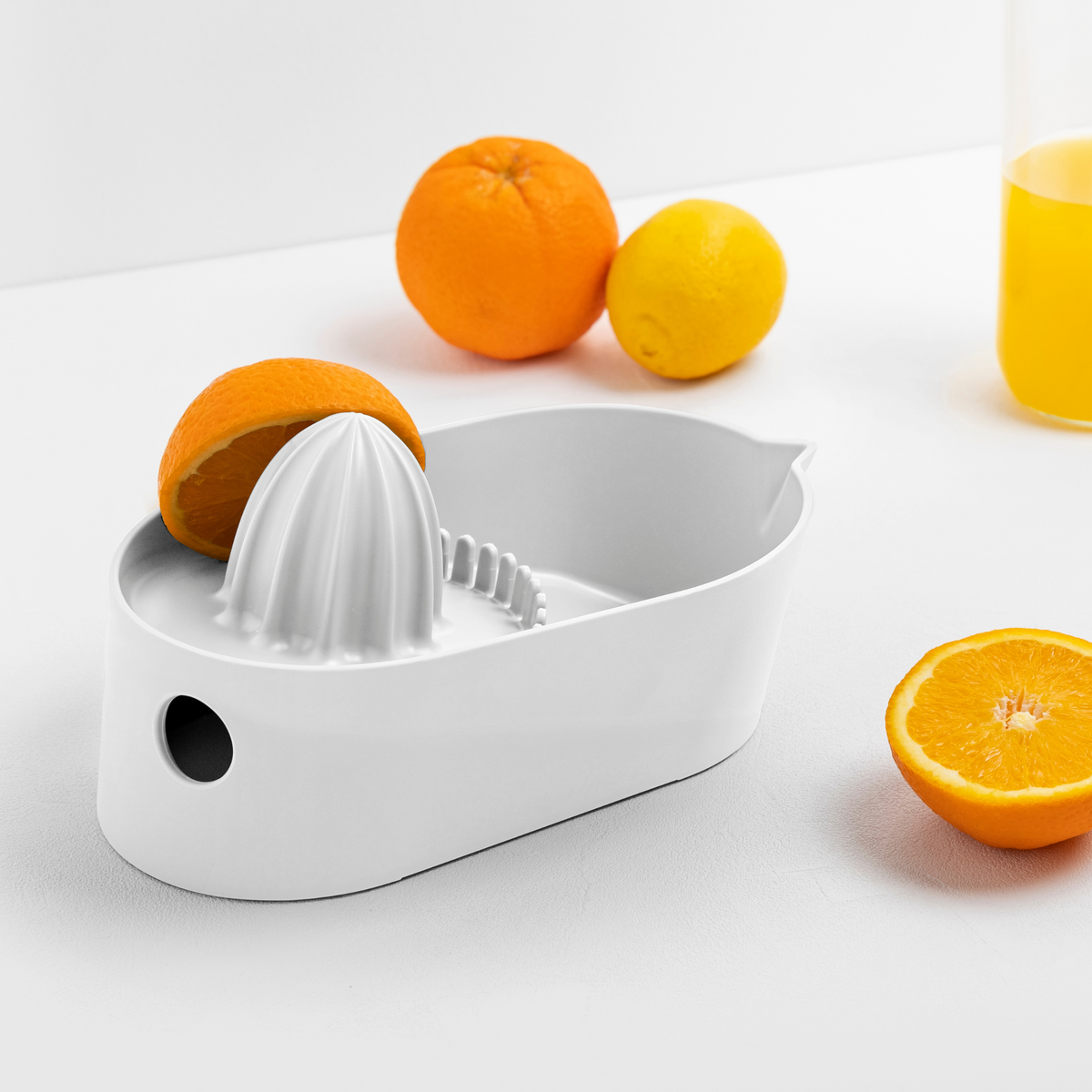 Blim+ Oblo' Juicer in white, beside fresh oranges