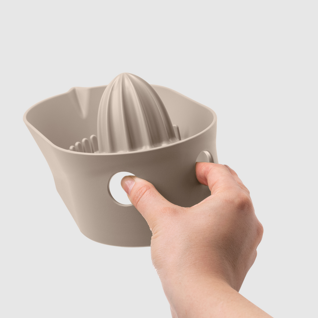 Blim+ Oblo' Juicer in taupe, held in a hand