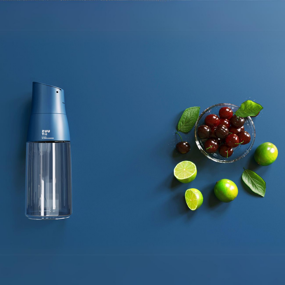 Zuutii Oil Dispenser in blue on a blue background beside olives and limes