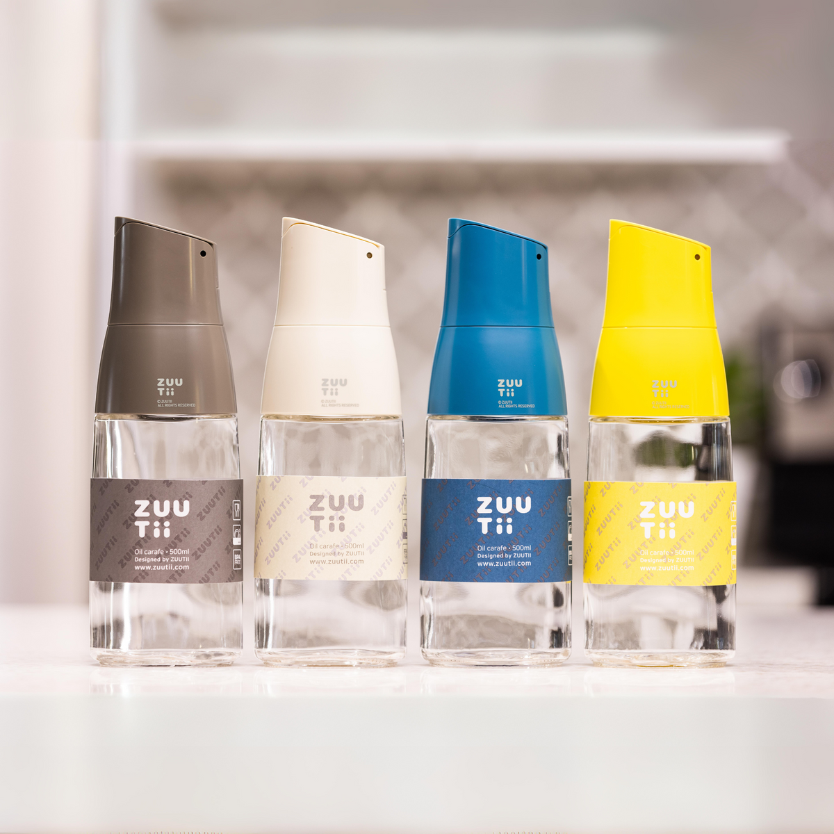 Zuutii Oil Dispenser in dark grey, cream, blue and yellow in a row