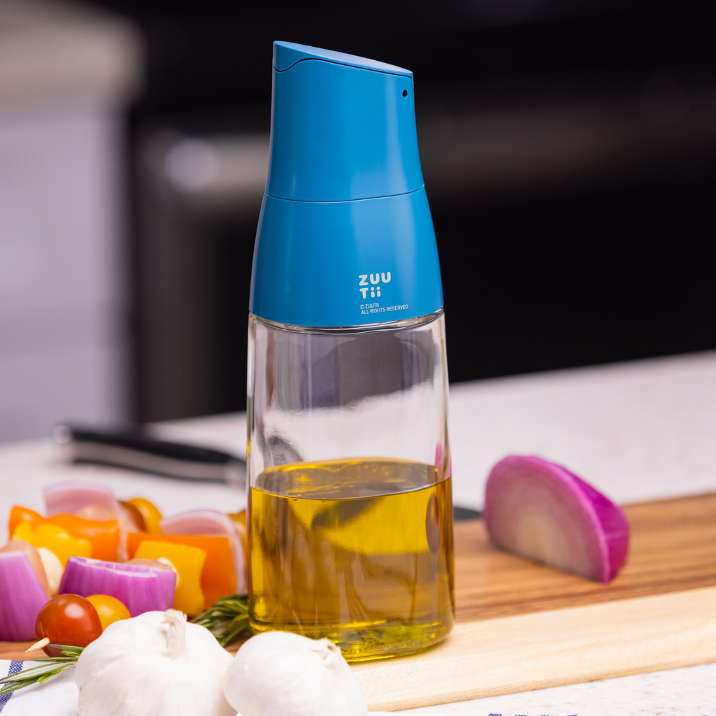 Zuutii Oil Dispenser in blue with olive oil beside chopped vegetables