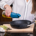 Zuutii Oil Dispenser in blue, tipping oil into a frying pan