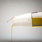 Zuutii Oil Dispenser in cream, pouring a thin stream of oil