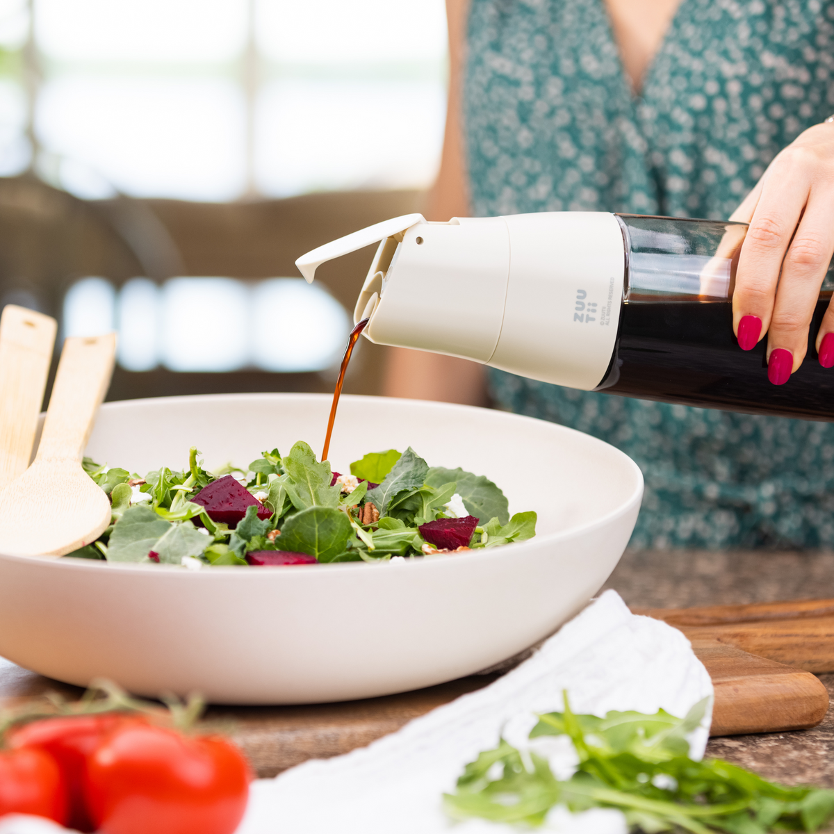 Zuutii Oil Dispenser in cream, drizzling dressing over a salad