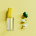 Zuutii Oil Dispenser in yellow on a yellow background beside limes