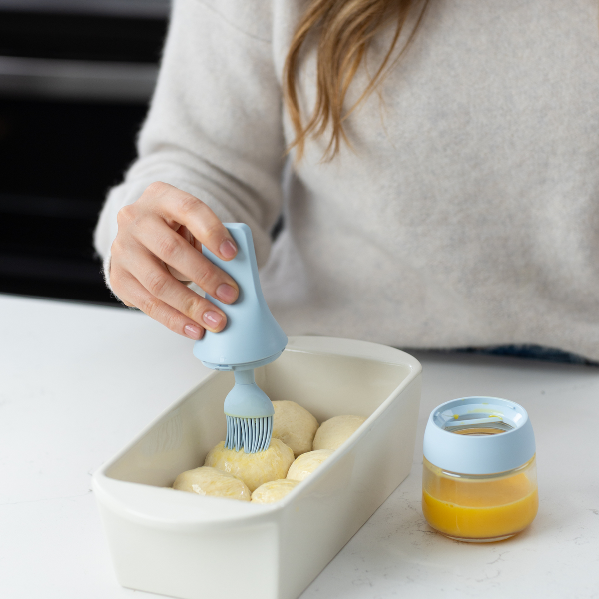 Zuutii Oil Dispenser with Brush in blue, a woman brushing melted butter in a dish