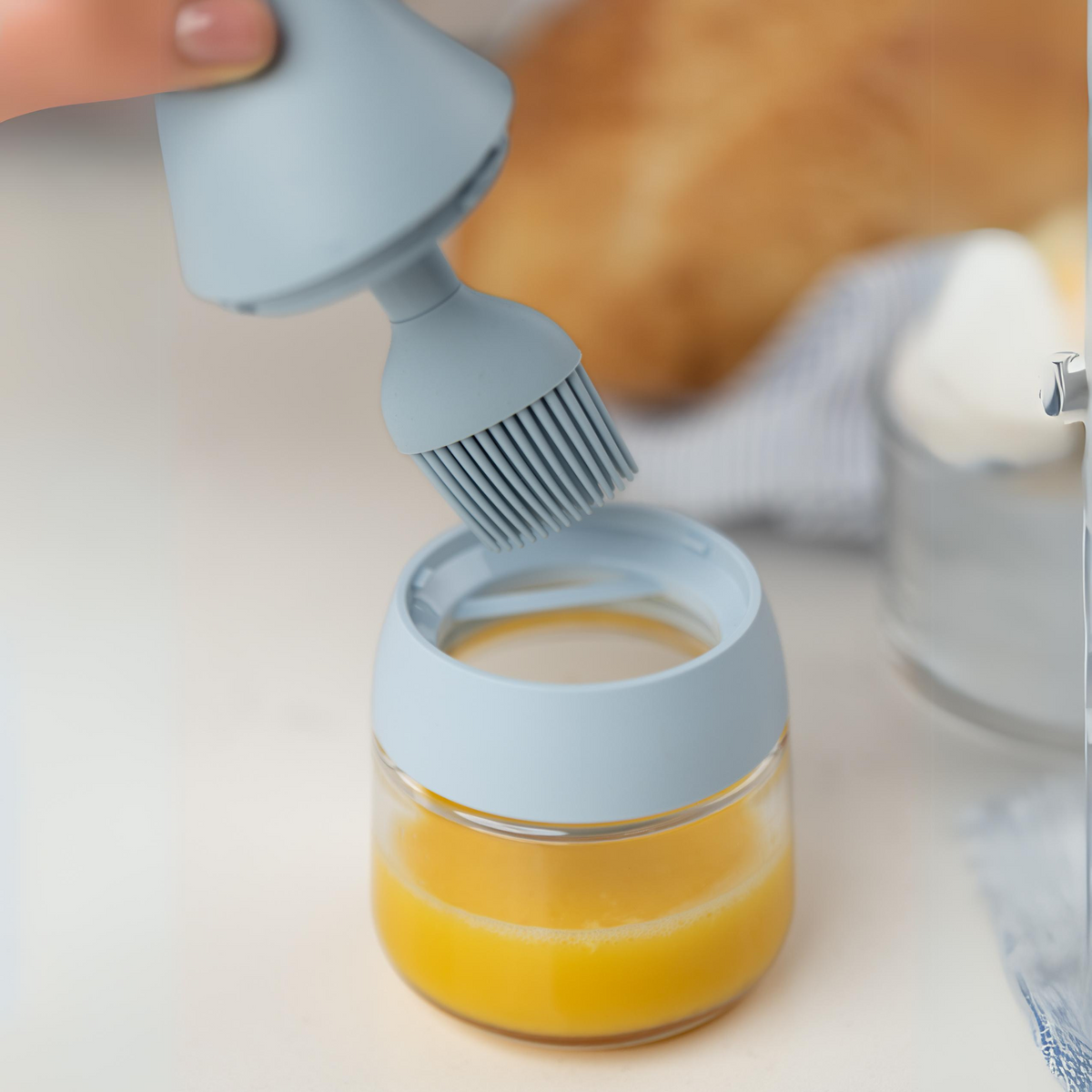 Zuutii Oil Dispenser with Brush in blue, with honey in the jar and the brush resting on top