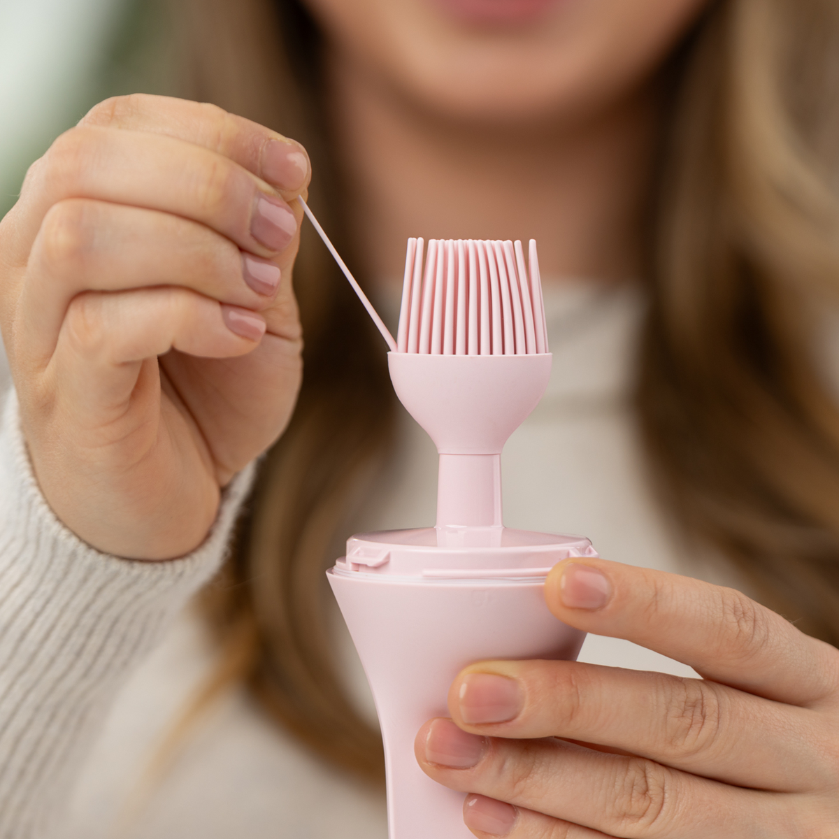 Zuutii Oil Dispenser with Brush in pink, a woman showing the silicone brush