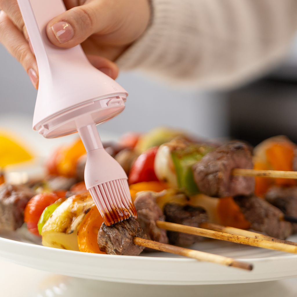 Zuutii Oil Dispenser with Brush in pink, brushing sauce over kebabs on a plate