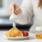Zuutii Oil Dispenser with Brush in cream, brushing a croissant on a plate