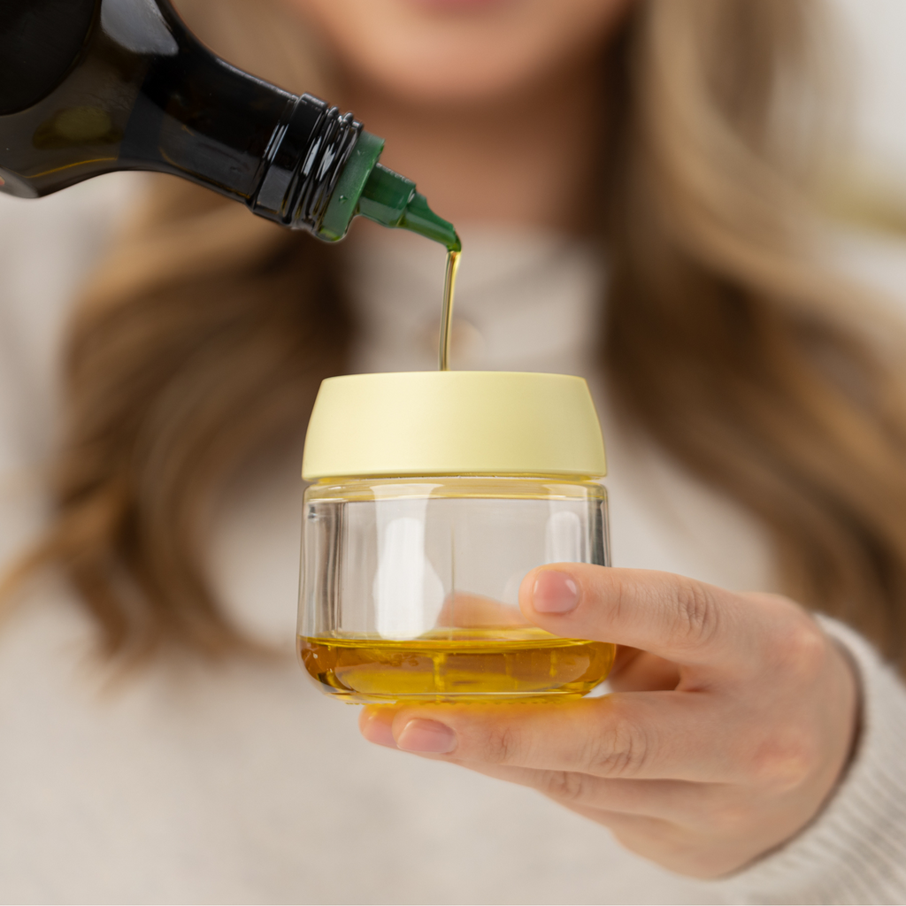 Zuutii Oil Dispenser with Brush in yellow, a woman pouring oil into the jar