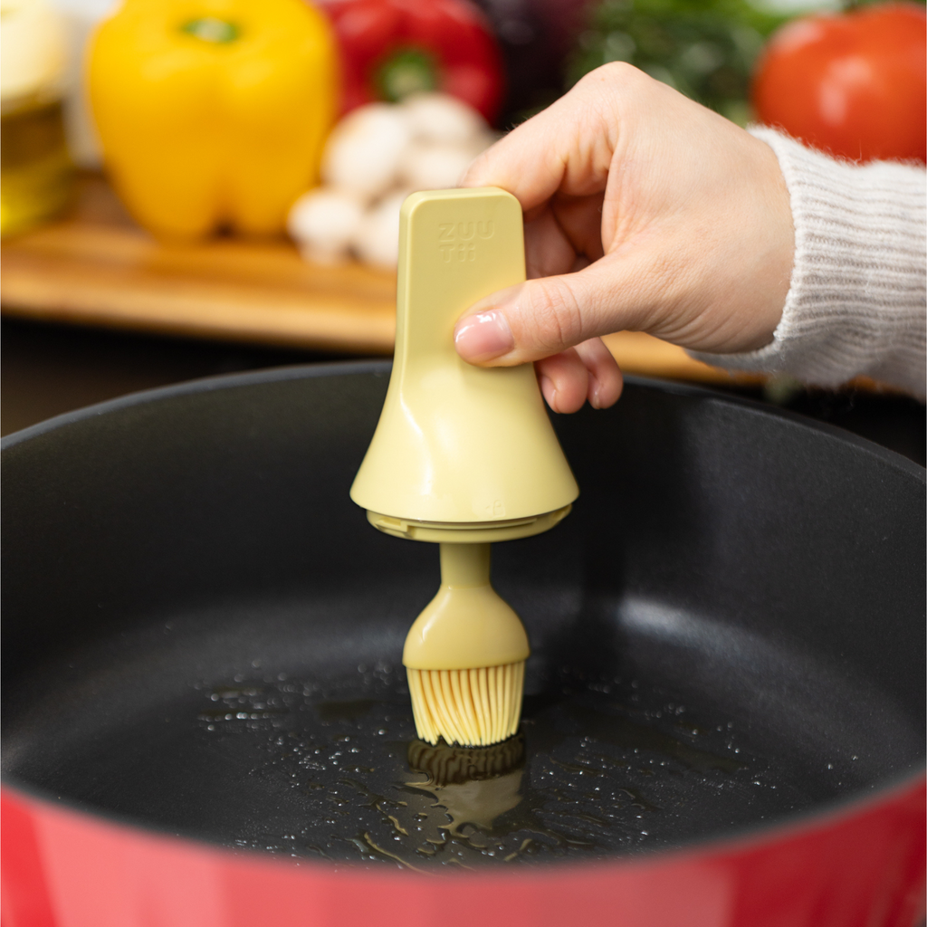 Zuutii Oil Dispenser with Brush in yellow, brushing oil in an empty red pan