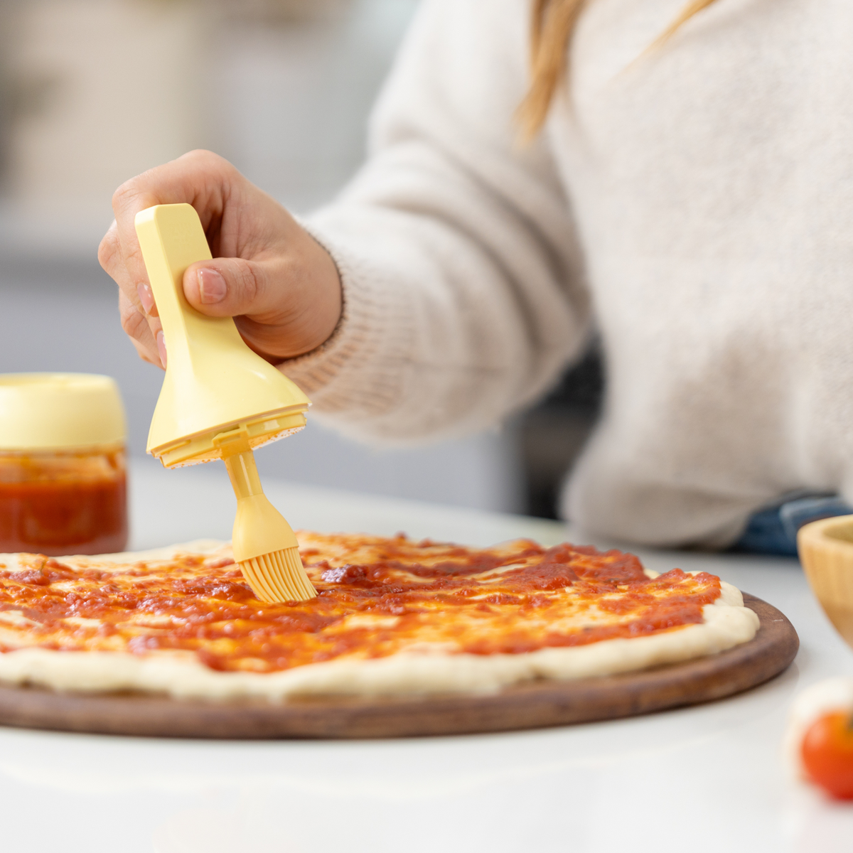 Zuutii Oil Dispenser with Brush in yellow, brushing oil onto a pizza base