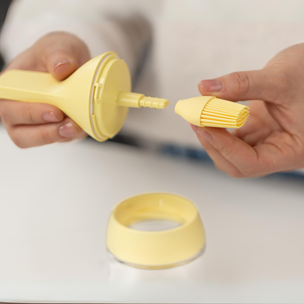 Zuutii Oil Dispenser with Brush in yellow, hands removing the brush from its holder