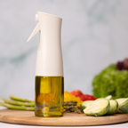 Zuutii Oil Sprayer in cream beside fresh vegetables on a wooden board