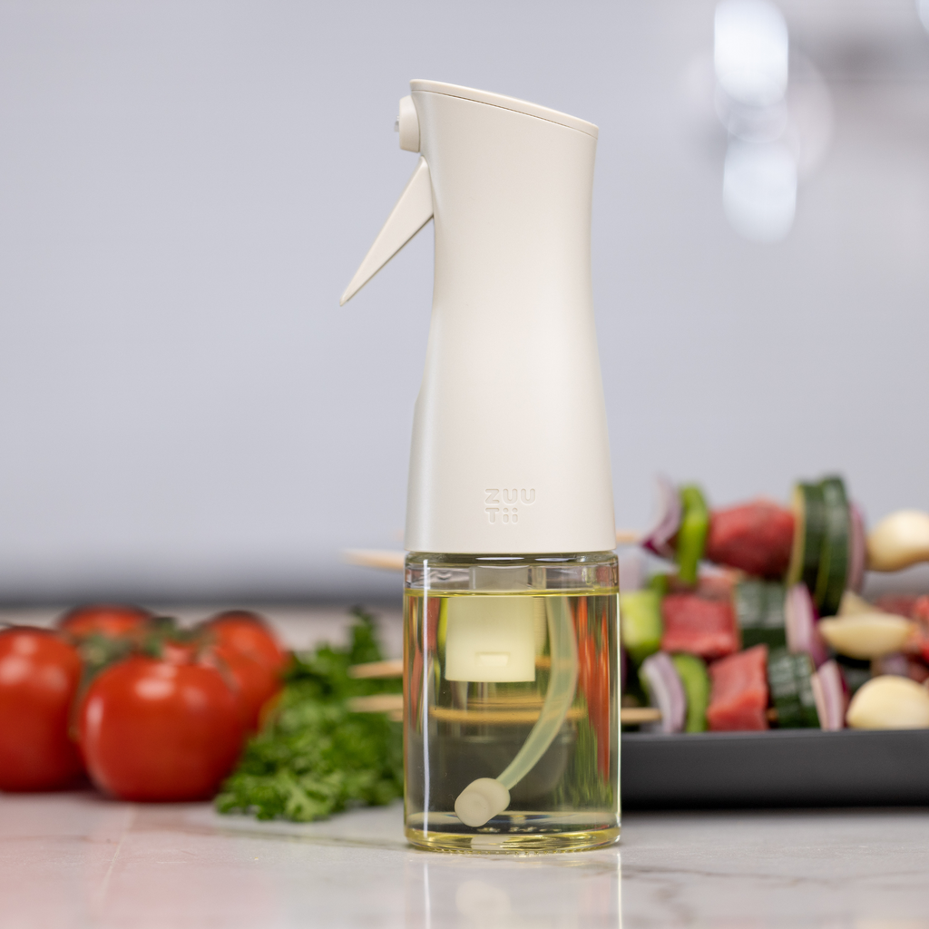 Zuutii Oil Sprayer in cream on a kitchen counter with vegetable skewers