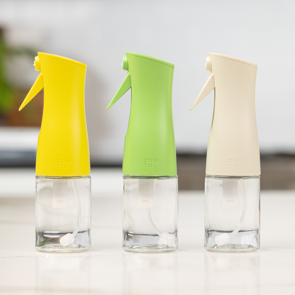 Zuutii Oil Sprayer in yellow, green and cream, empty, on a white surface