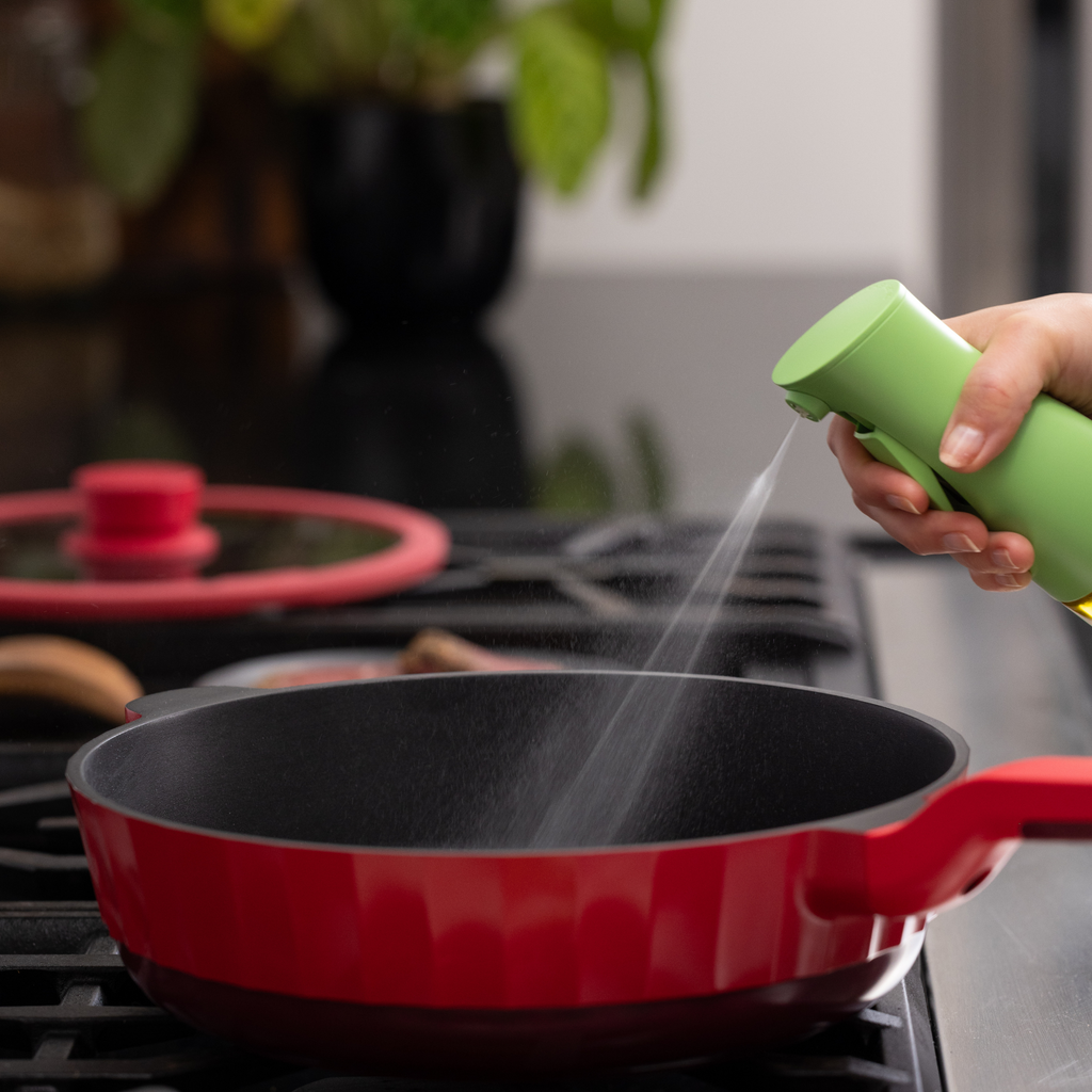 Zuutii Oil Sprayer in green, spraying oil into a red frying pan