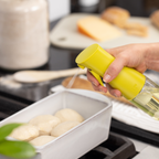 Zuutii Oil Sprayer in yellow, spraying oil over a dish