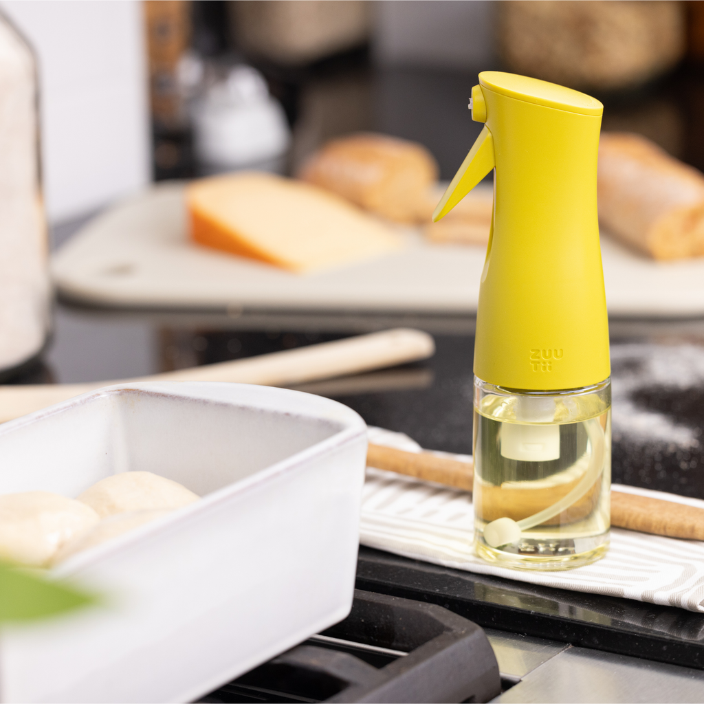 Zuutii Oil Sprayer in yellow beside a baking dish on a kitchen counter