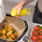Zuutii Oil Sprayer in yellow, spraying oil over roast chicken in a cooking basket