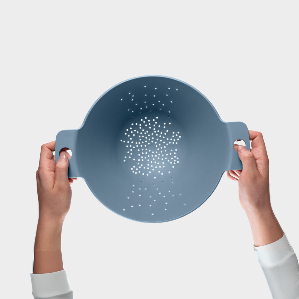 Blim+ Cosmo Colander Medium in blue, held up in both hands, seen from the front